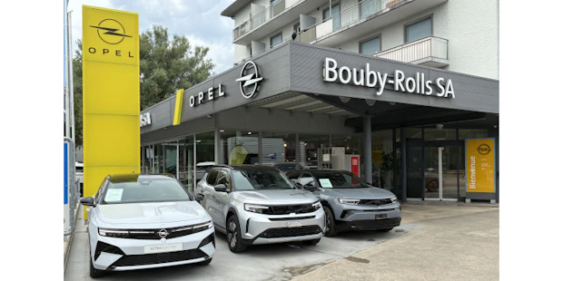 Bouby-Rolls SA, Opel-Partner in der Region: modernes Autohaus mit Opel-Logo, Firmenbeschriftung und drei ausgestellten Fahrzeugen im Eingangsbereich.